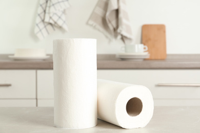 Photo of Rolls of paper towels on light grey marble table in kitchen