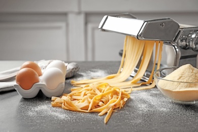 Photo of Pasta maker with dough and eggs on kitchen table