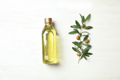 Photo of Flat lay composition with bottle of oil and olive tree twig on white wooden background