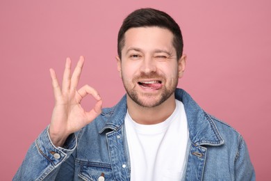Photo of Happy man showing his tongue and OK gesture on pink background