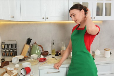 Photo of Thoughtful woman near messy countertop with dishware, utensils and food in kitchen