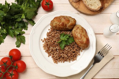 Photo of Tasty buckwheat with parsley and cutlets on wooden table, flat lay