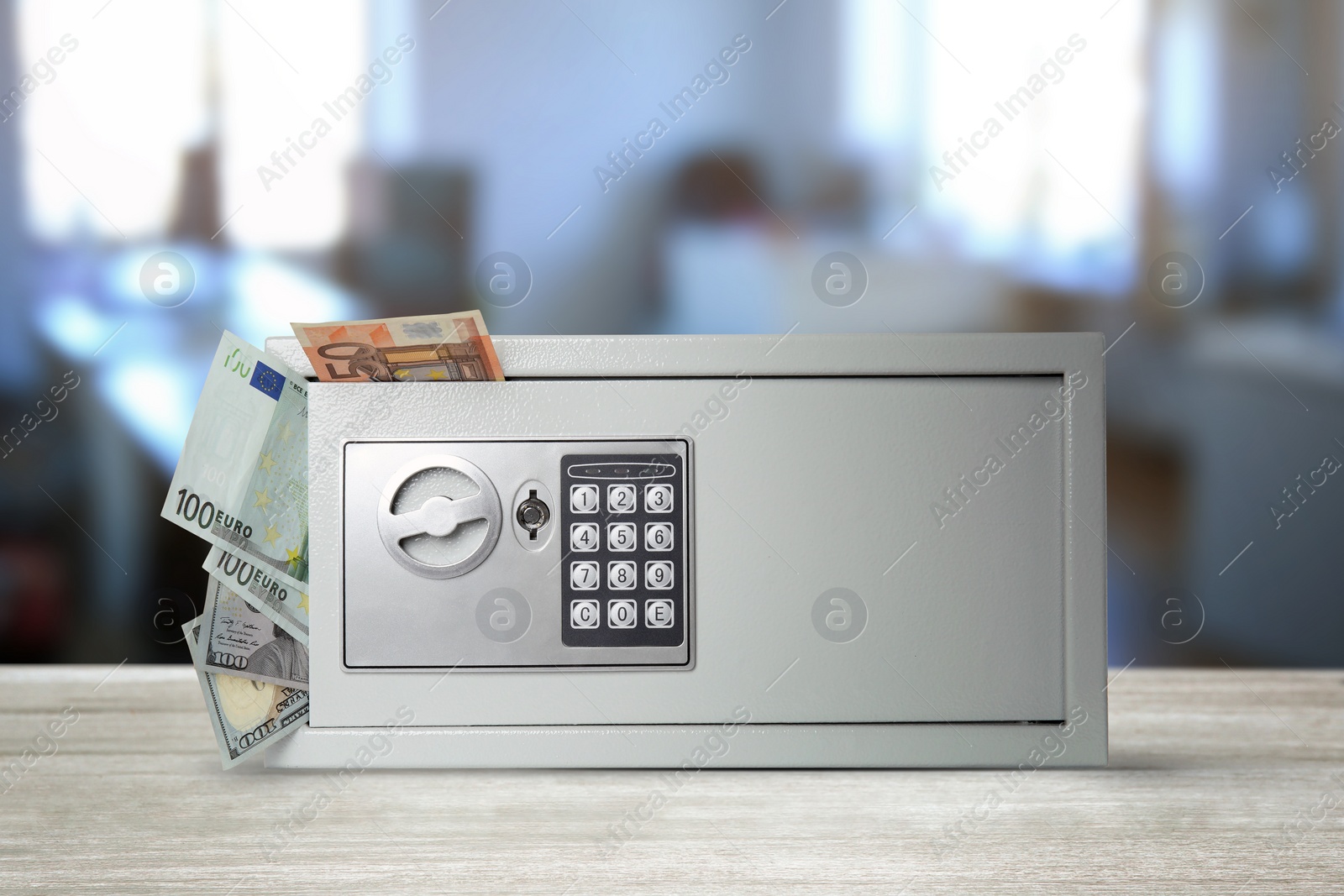 Image of Closed steel safe with electronic lock and money on white wooden table indoors