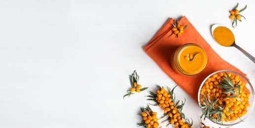 Image of Delicious sea buckthorn jam and fresh berries on white wooden table, flat lay. Banner design with space for text