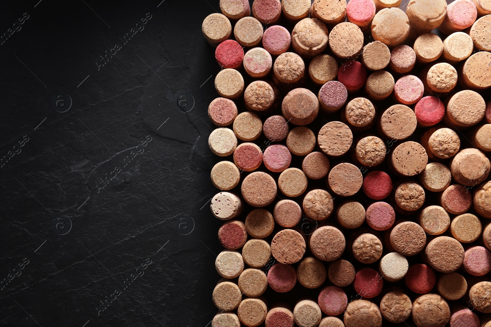 Photo of Many wine bottle corks on black table, flat lay. Space for text