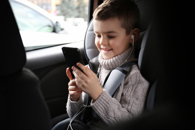 Cute little boy listening to audiobook in car