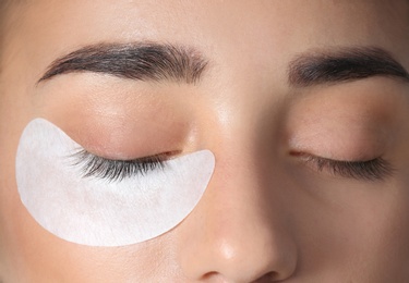 Photo of Young woman undergoing eyelashes extensions procedure, closeup