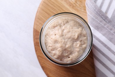 Photo of Sourdough starter in glass jar on light table, top view. Space for text
