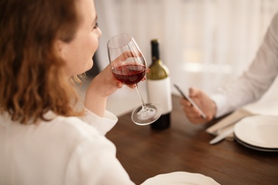 Photo of Woman with glass of wine at table in restaurant