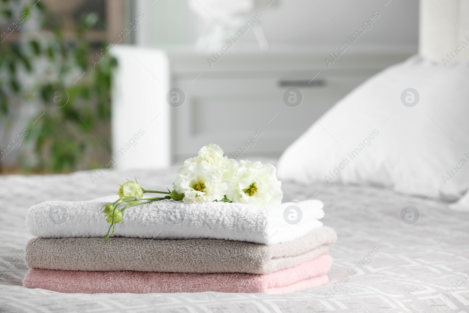 Photo of Terry towels with beautiful flowers on bed indoors, space for text