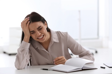 Stressed young woman at table in office