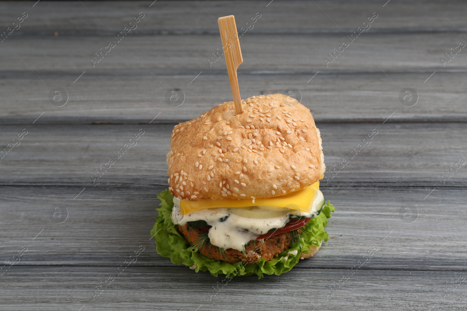 Photo of Delicious vegetarian burger on grey wooden table