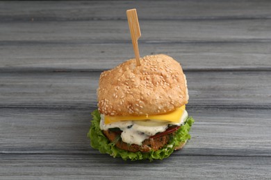 Photo of Delicious vegetarian burger on grey wooden table