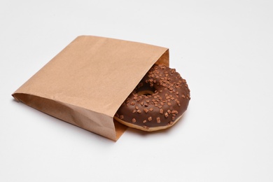 Photo of Paper bag with chocolate doughnut on white background. Space for text