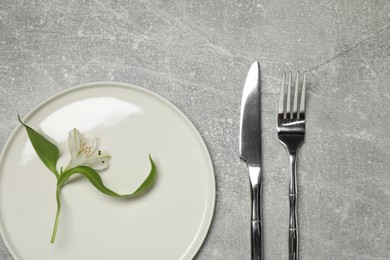 Photo of Setting with beautiful cutlery on grey textured table, top view