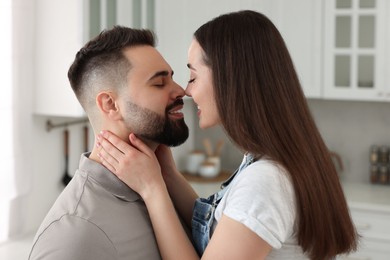 Photo of Affectionate young couple kissing in light kitchen