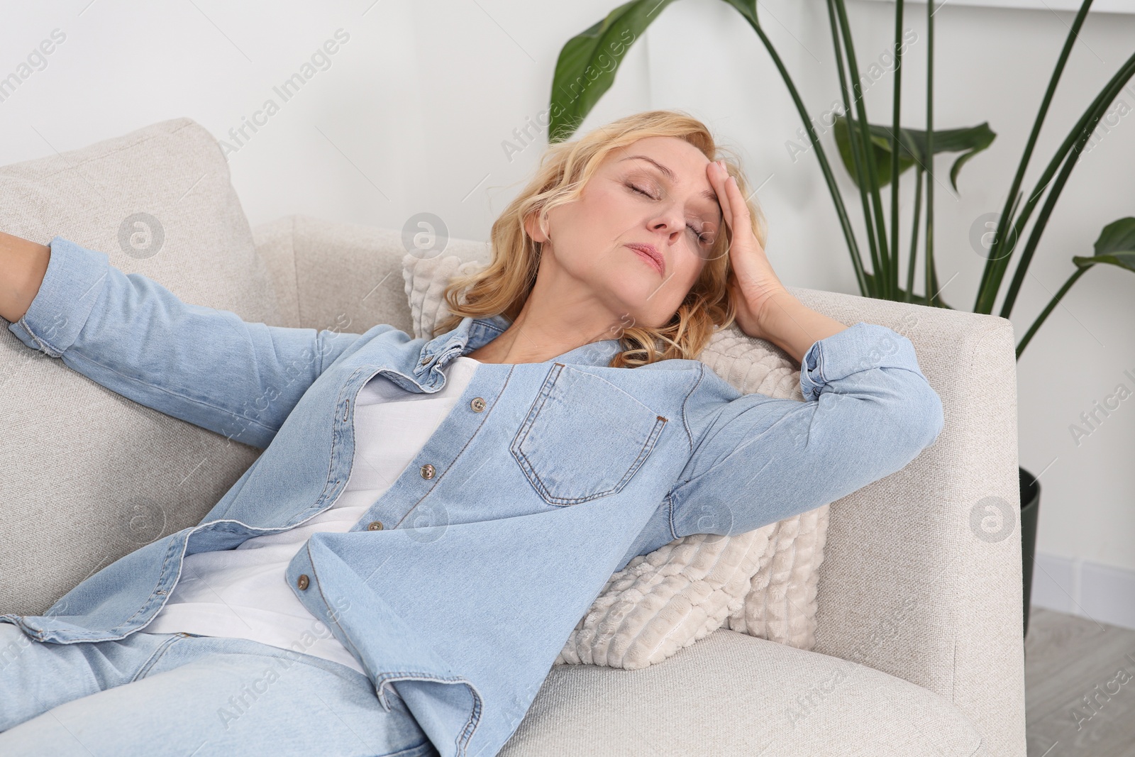 Photo of Woman suffering from headache on sofa at home. Hormonal disorders