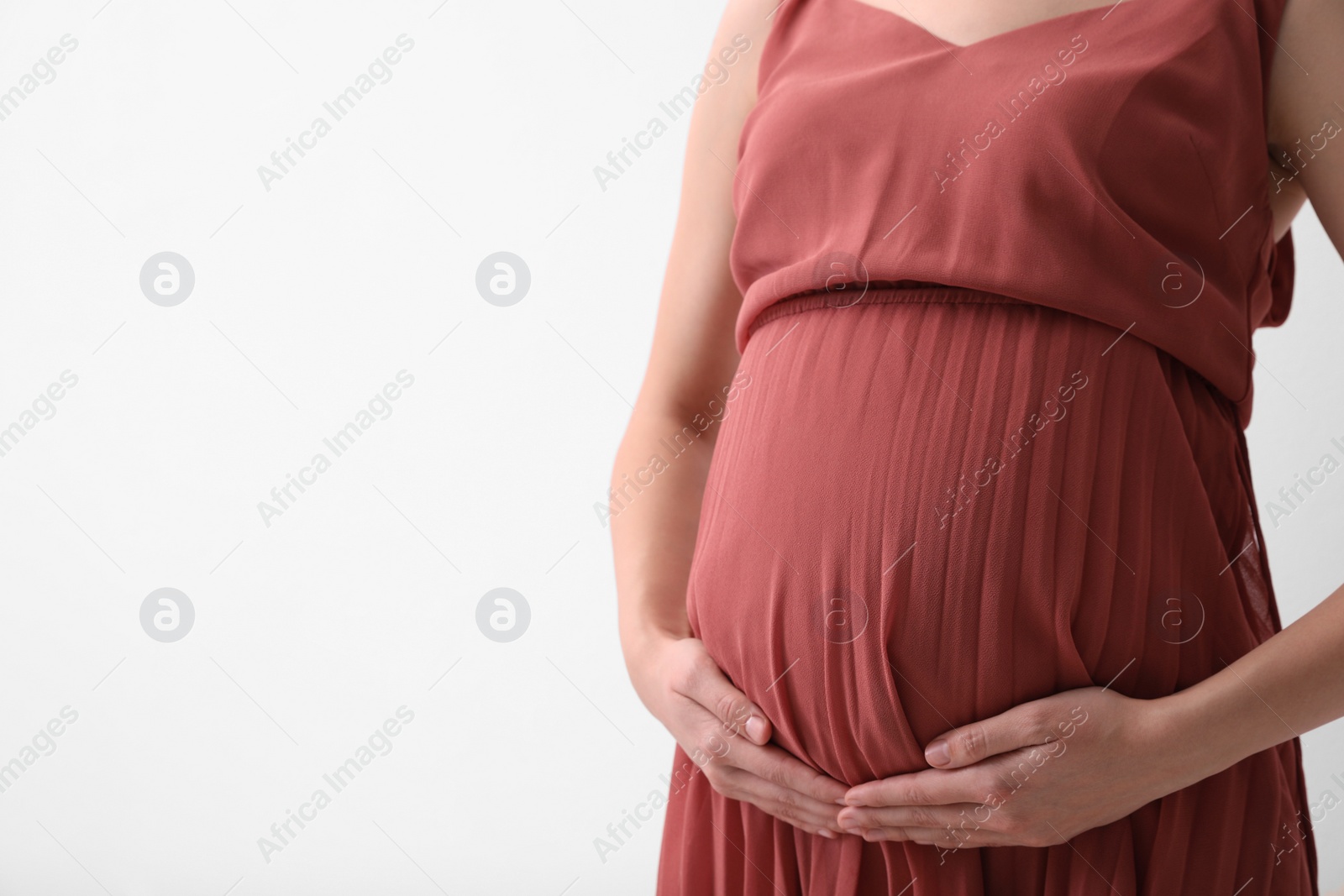 Photo of Young pregnant woman on light background, closeup. Space for text