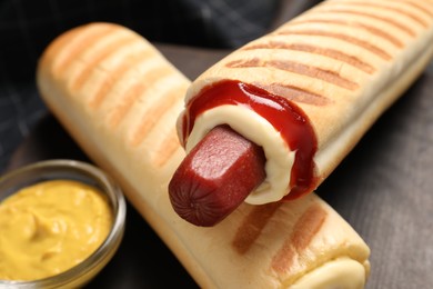 Photo of Delicious french hot dogs and dip sauce on table, closeup