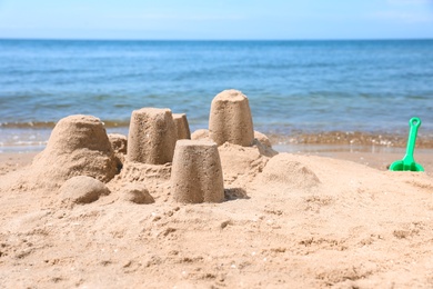 Photo of Little sand figures on beach near sea. Space for text