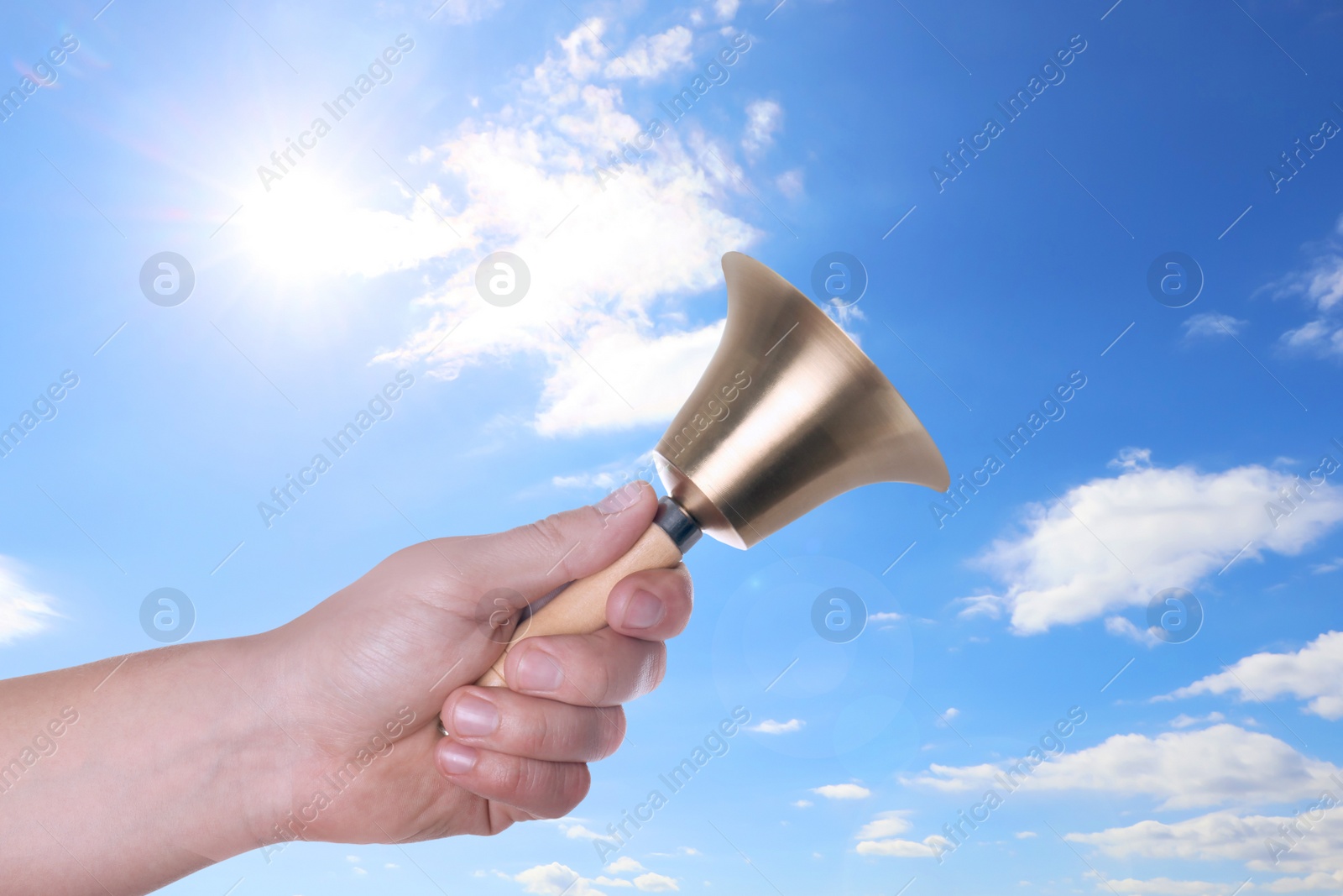 Image of Woman with school bell against blue sky, closeup