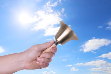 Image of Woman with school bell against blue sky, closeup