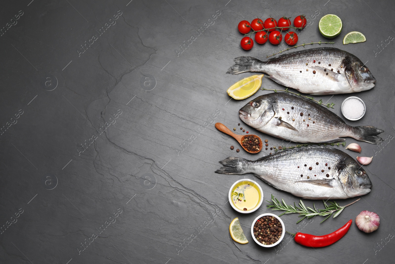 Photo of Flat lay composition with fresh raw dorado fish and ingredients on black table, space for text