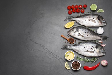 Flat lay composition with fresh raw dorado fish and ingredients on black table, space for text