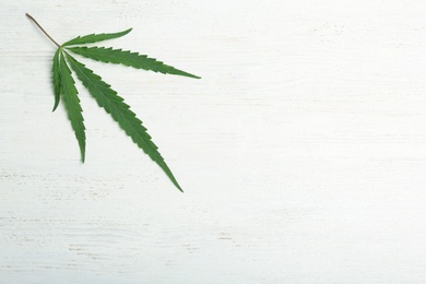 Photo of Hemp leaf and space for text on white wooden background, top view