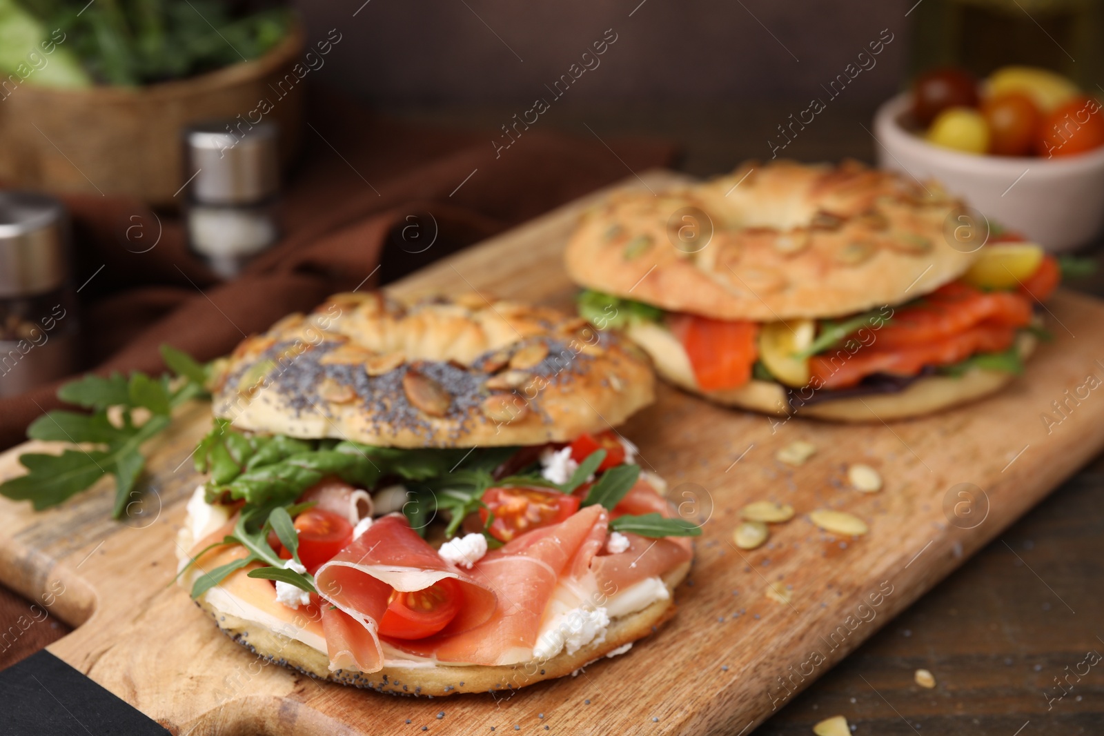 Photo of Wooden board with tasty bagel sandwiches on table, closeup