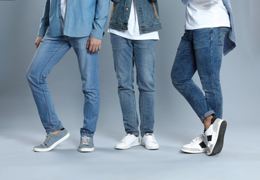 Photo of Group of young men in stylish jeans on grey background, closeup