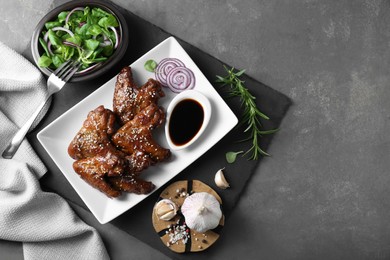 Photo of Chicken wings glazed with soy sauce served on grey table, flat lay. Space for text