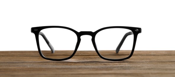 Photo of Stylish glasses with black frame on wooden table against white background
