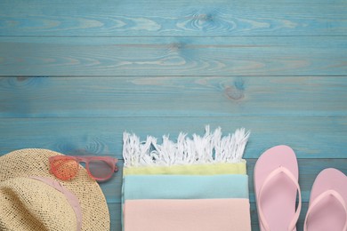 Photo of Beach towel, flip flops, straw hat and sunglasses on light blue wooden background, flat lay. Space for text
