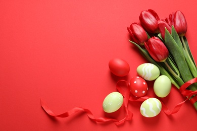 Photo of Flat lay composition of painted Easter eggs and spring flowers on color background, space for text