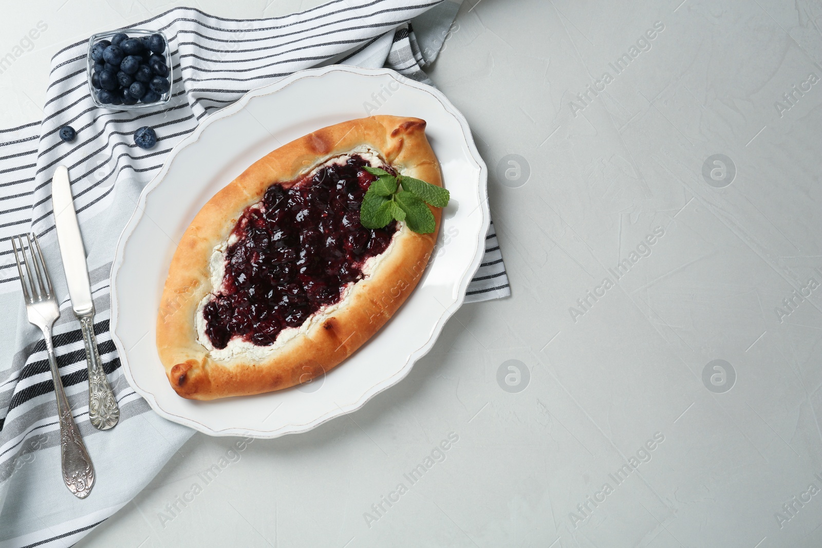 Photo of Delicious sweet cottage cheese pastry with cherry jam served on light table, flat lay. Space for text