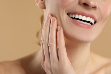 Woman with healthy skin on beige background, closeup