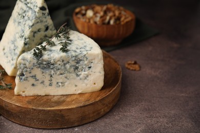 Photo of Tasty blue cheese with thyme on brown table. Space for text