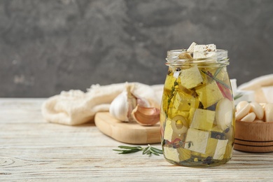 Photo of Composition with pickled feta cheese in jar on white wooden table, space for text