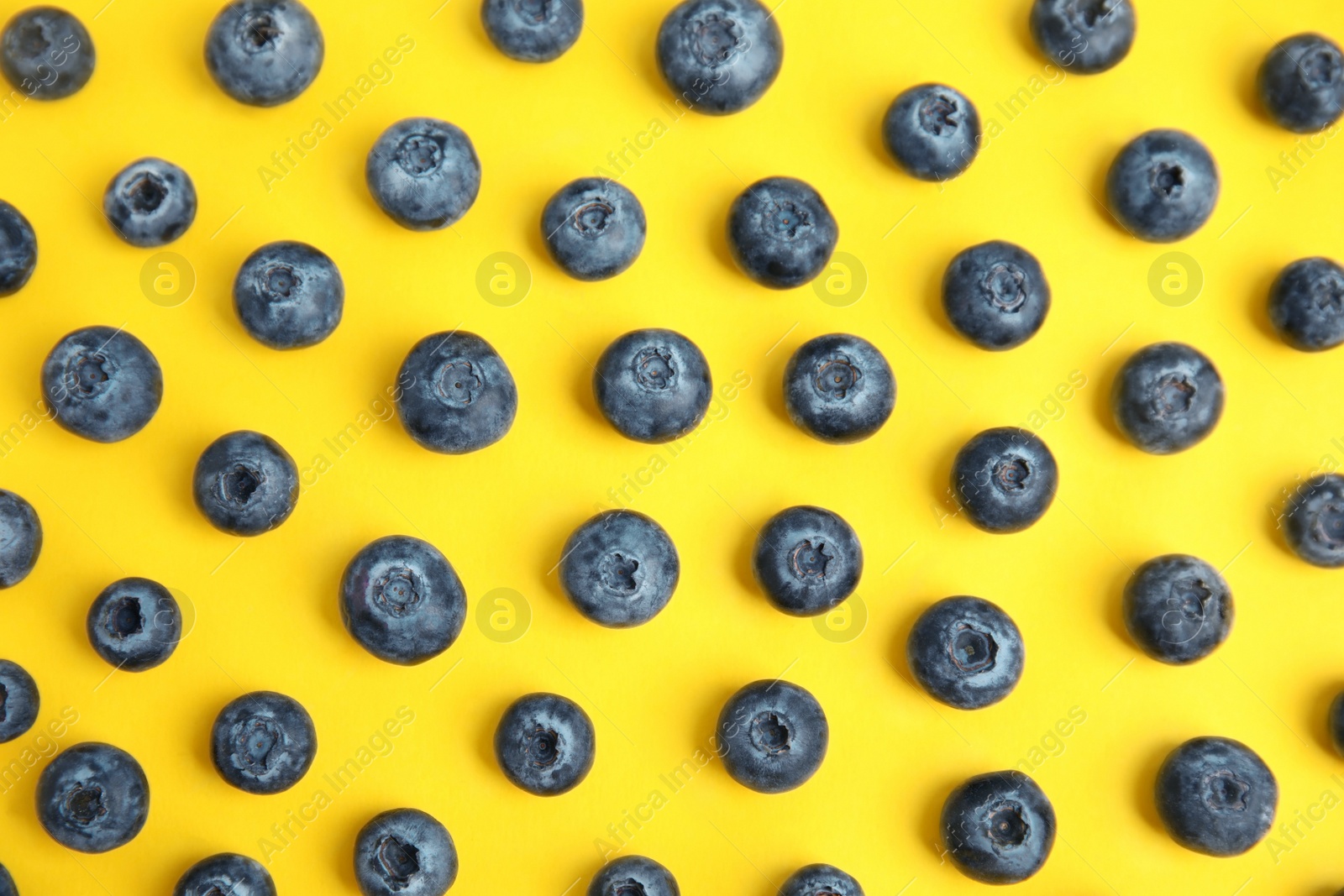 Photo of Fresh ripe blueberries on yellow background, flat lay