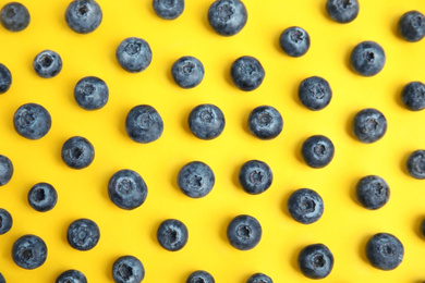 Fresh ripe blueberries on yellow background, flat lay