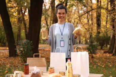 Portrait of volunteer packing food products at table in park