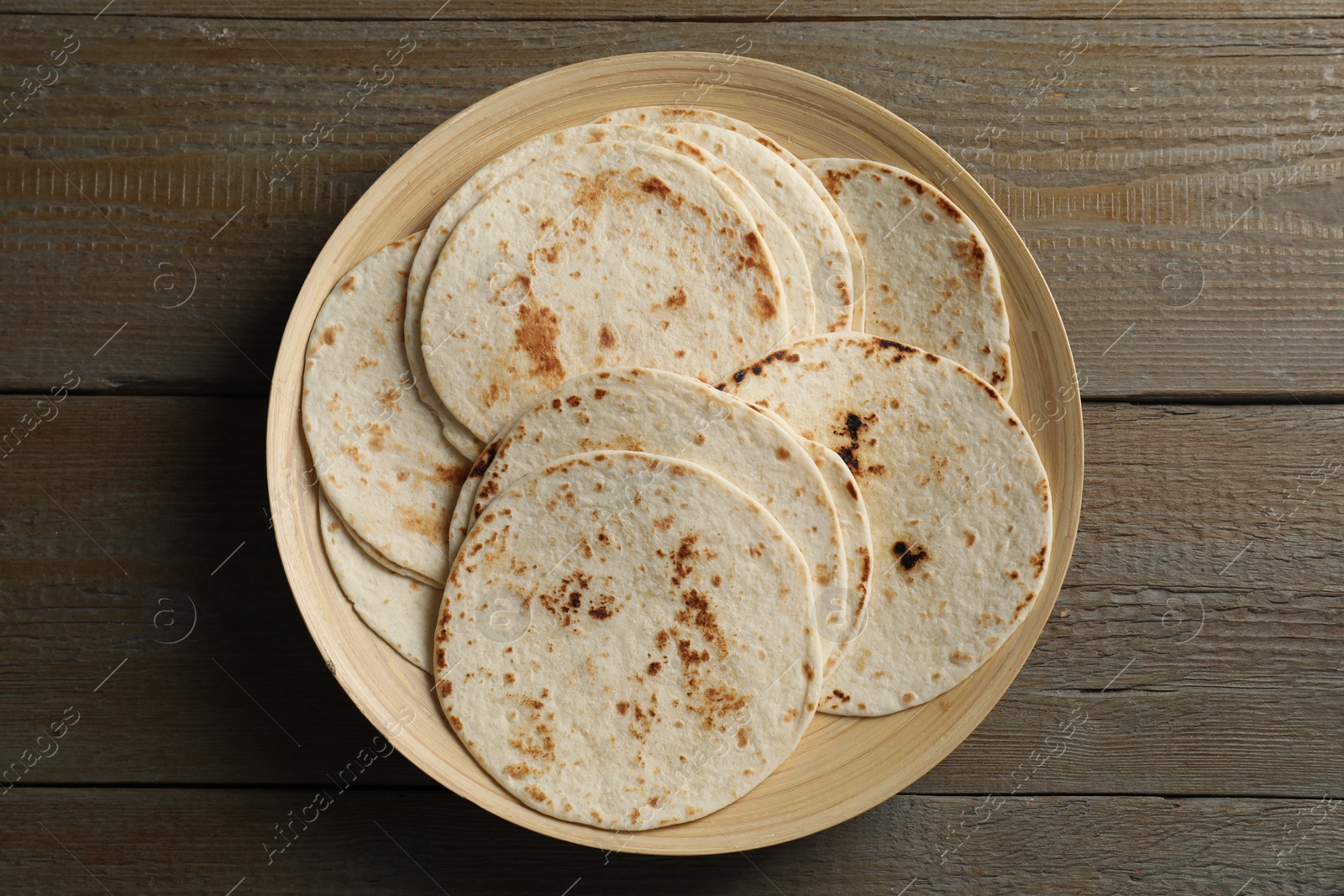 Photo of Many tasty homemade tortillas on wooden table, top view