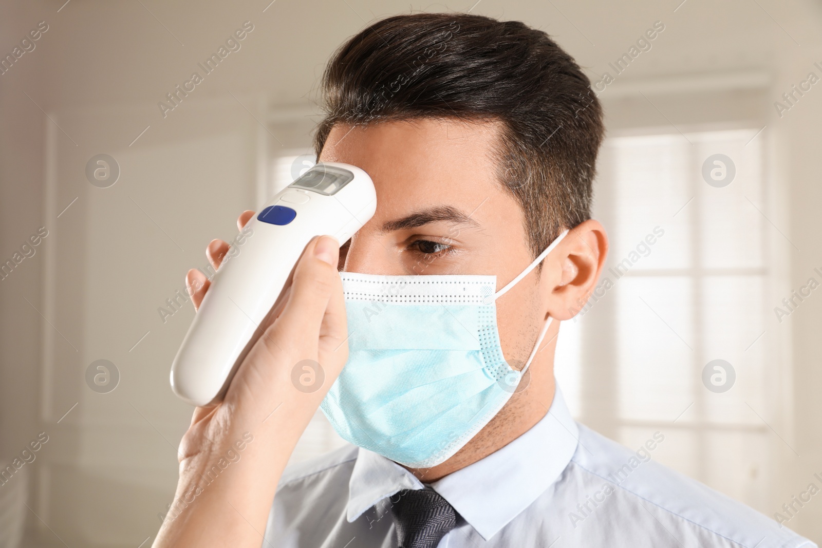 Photo of Doctor measuring man's temperature in office closeup. Prevent spreading of Covid-19