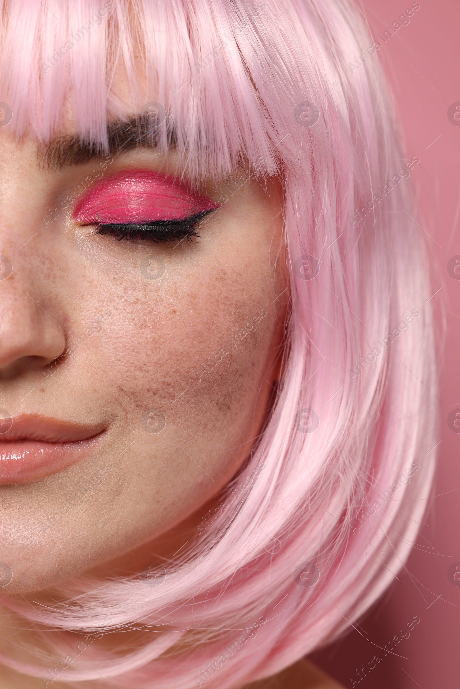 Photo of Beautiful woman with bright makeup and fake freckles on pink background, closeup