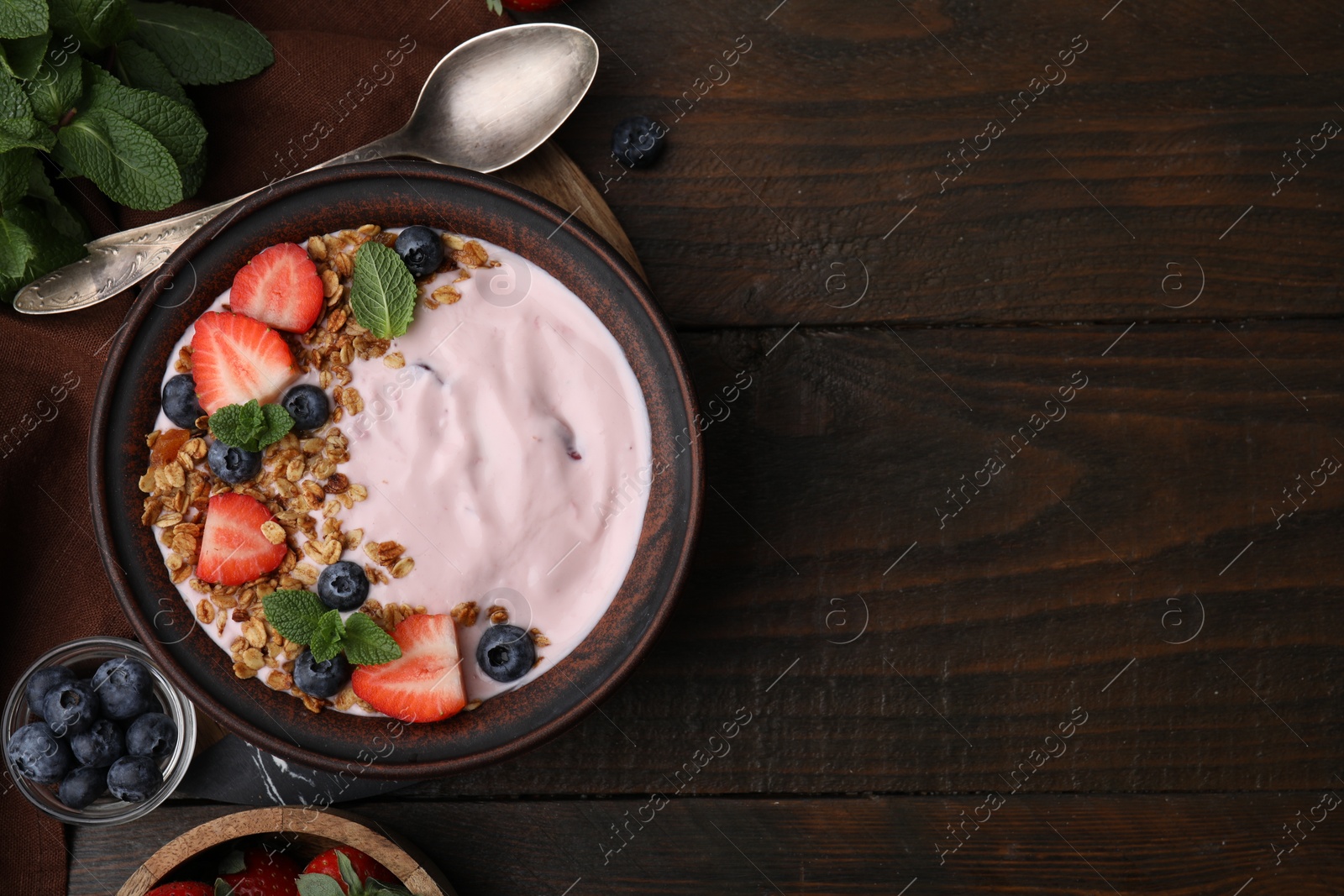 Photo of Bowl with yogurt, berries and granola on wooden table, flat lay. Space for text