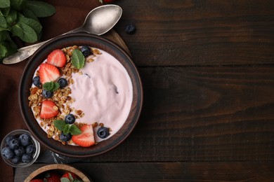 Bowl with yogurt, berries and granola on wooden table, flat lay. Space for text