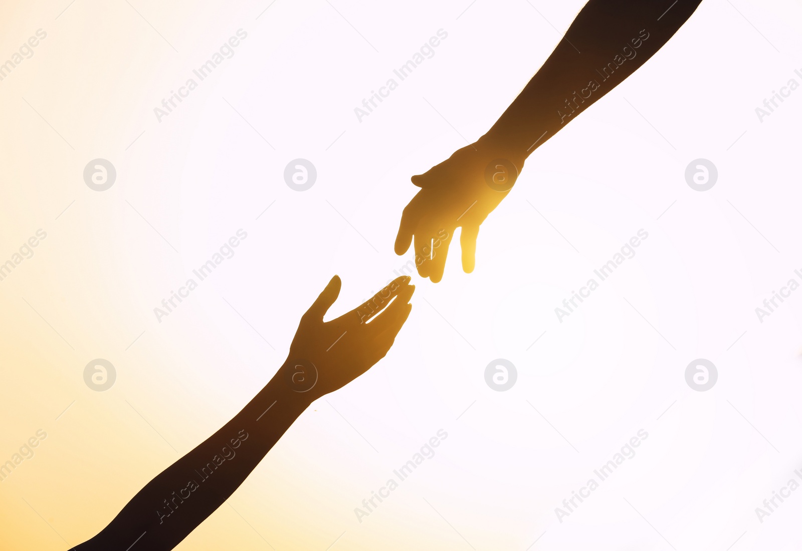 Photo of Silhouettes of man and woman helping each other against sunset, closeup