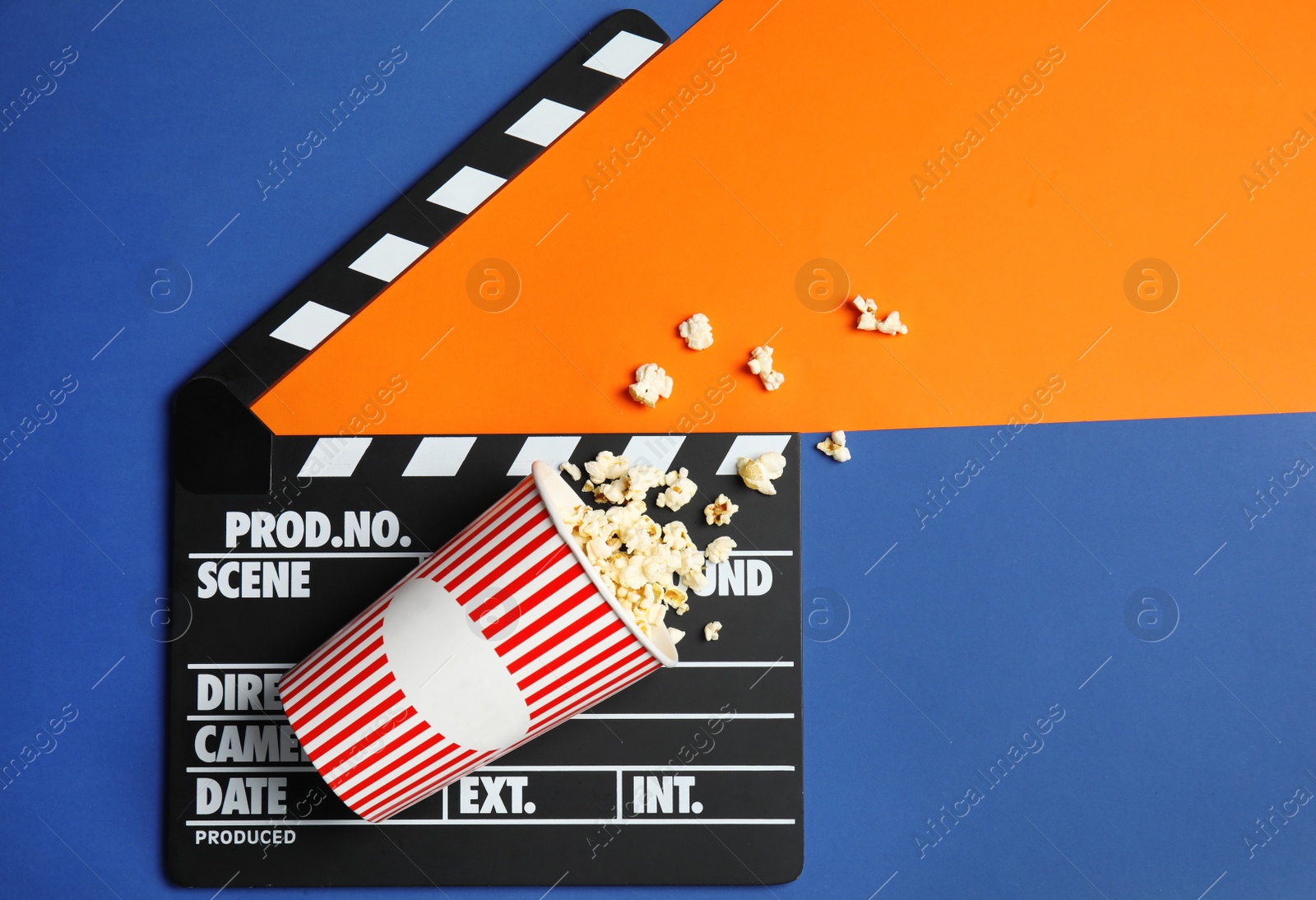 Photo of Flat lay composition with popcorn, cinema clapperboard and space for text on color background