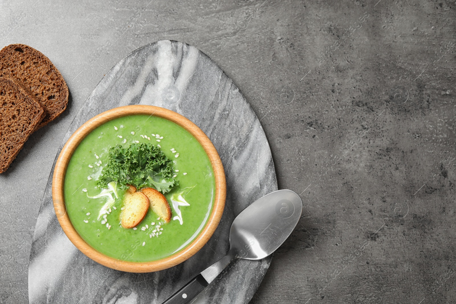 Photo of Tasty kale soup served on grey table, flat lay. Space for text